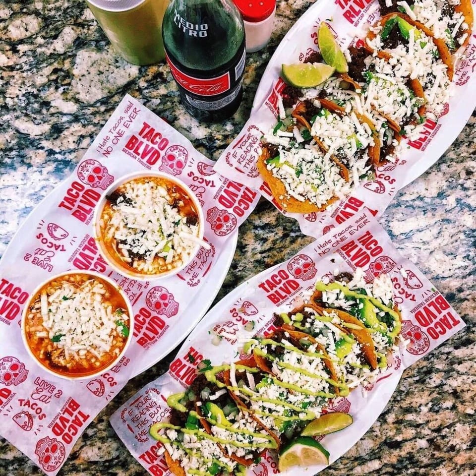 Overhead view of Taco Blvd tacos and birria, with a Coca-Cola bottle on a granite counter.