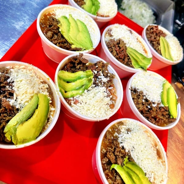 Multiple Taco Blvd taco bowls with meat, cheese, and avocado slices on a red tray.